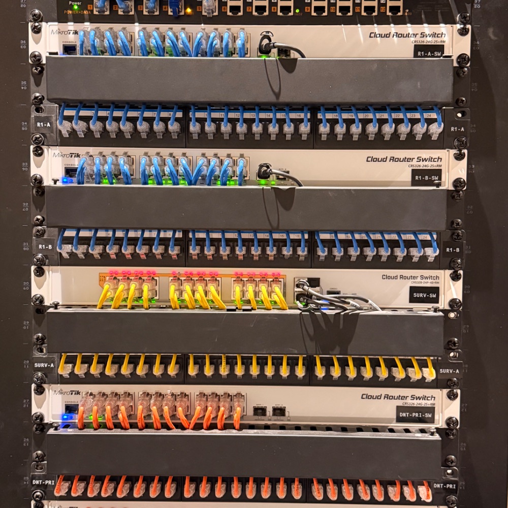 MikroTik managed network rack with color-coded VLAN structured cabling — separate networks for staff, worship team, and security cameras — at Reach Church, Hyannis
